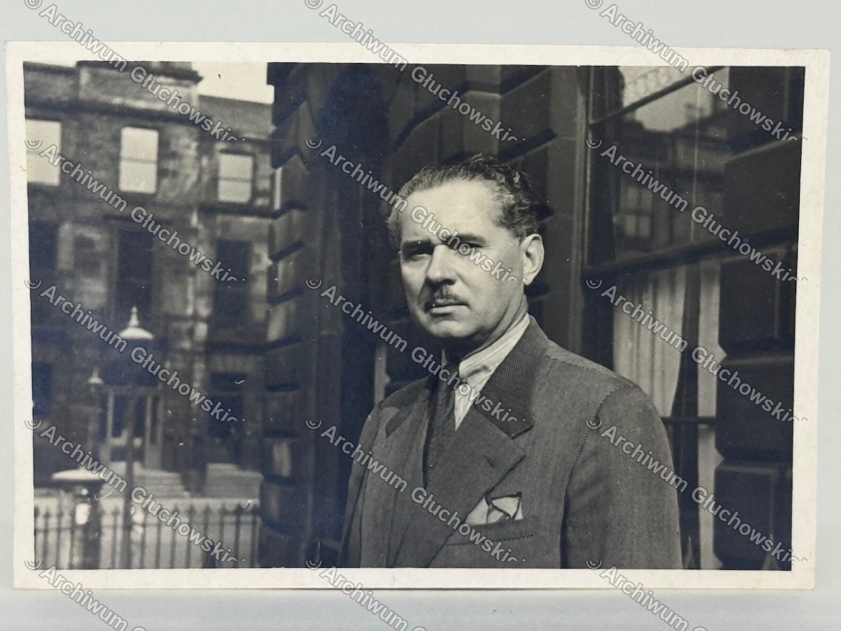 Fotografia portretowa — mężczyzna w ubraniu cywilnym na tle szkockiej architektury (identyfikowany jako Kazimierz Gedymin Jurgielewicz, 1891–1956)